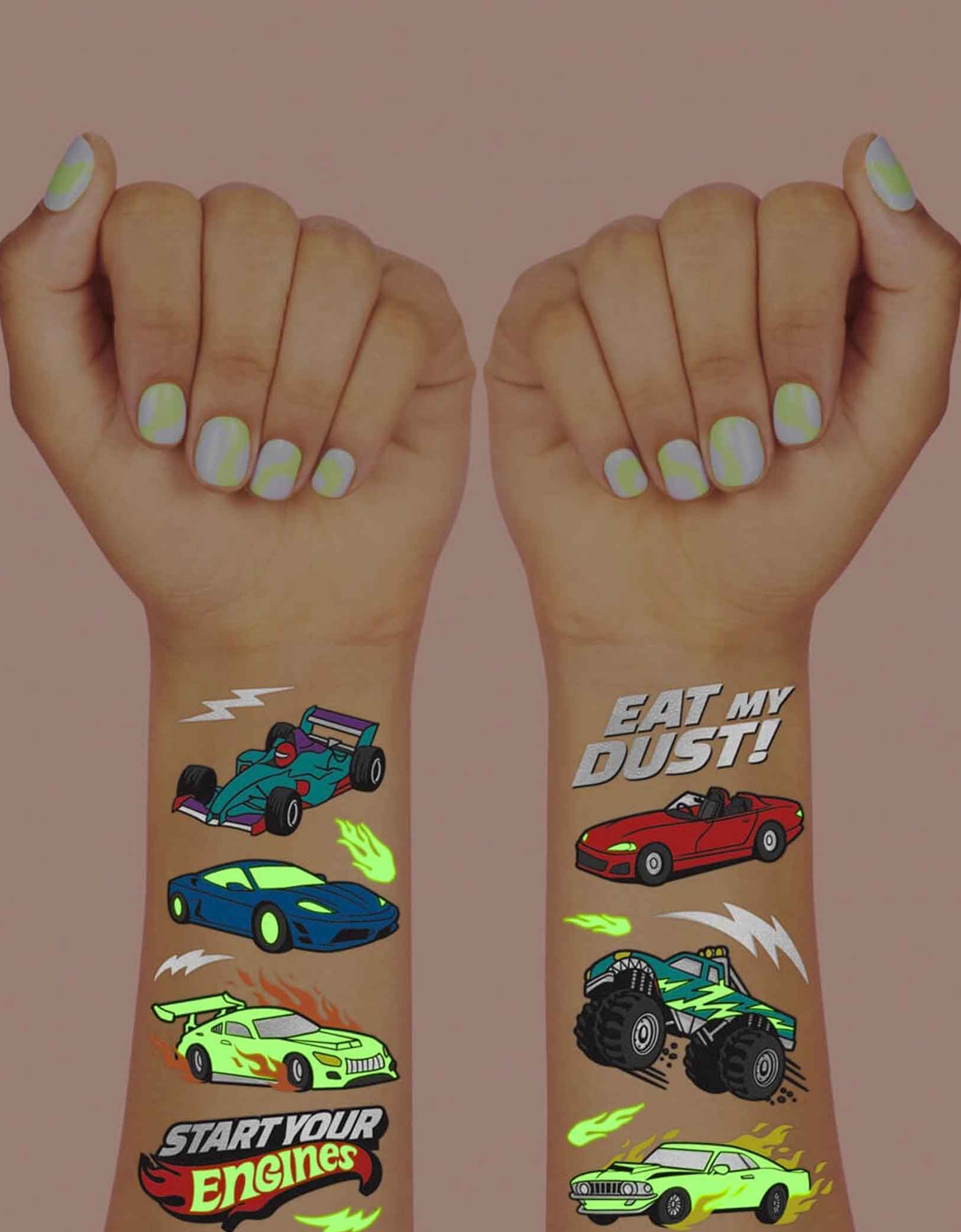 Two hands with colorful race car themed temporary tattoos from Momo Party with text "Eat my dust" & "Start Your Engines" glow in the dark on a dark background.