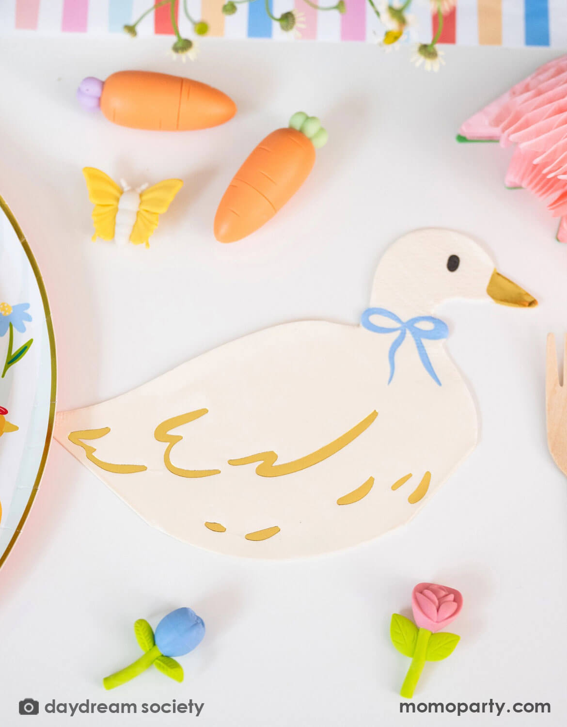 Momo Party's 4.5" x 7.5" Silly Goose Goose Shaped Large Napkin with a blue bow by Daydream Society with mini carrot pens, and mini butterfly and flower shaped erasers by Daydream Society on a white background with colorful accents.