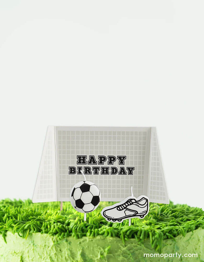 Momo Party's Goal Cake Topper & Candle Set by Hooty Balloo on a green cake decorated with buttercream on the top which looks like the soccer field grass. This set includes one cake topper and two candles in soccer ball shape and soccer shoe shape. This champion addition will kick your party up a notch with its playful soccer design and candle feature. Perfect for any soccer fan, this set is a must-have for any goal-oriented gathering.
