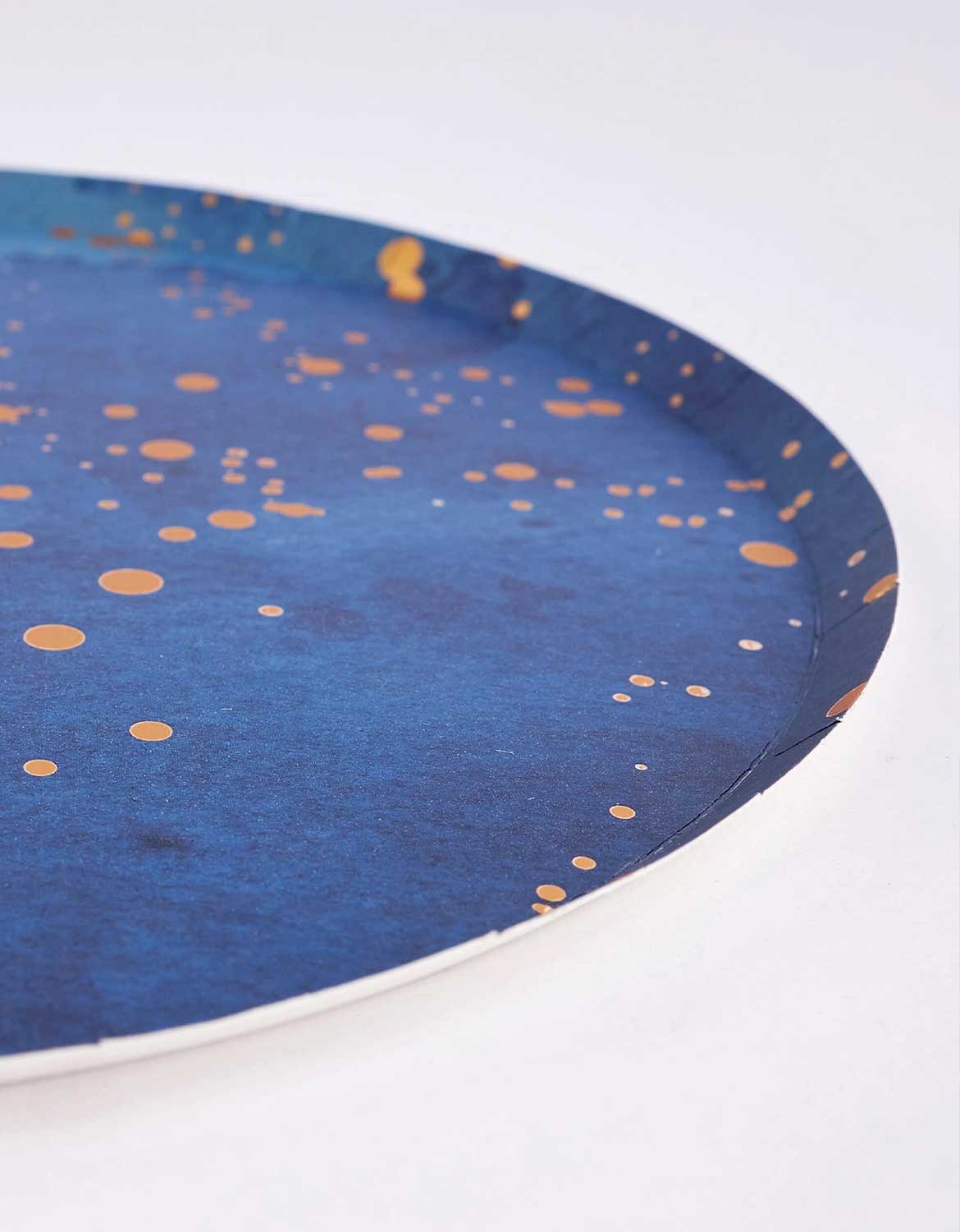 A close up profile shot of Momo Party's 10" Blue Gold Dust Large Paper Plate with gold speckles on a white background.