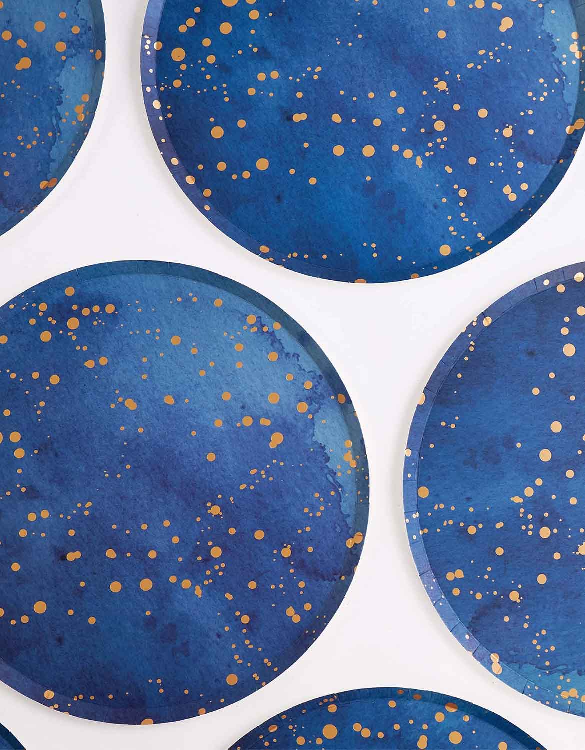 Multiple of Momo Party's 10" Blue Gold Dust Large Paper Plates with gold speckles on a white background.