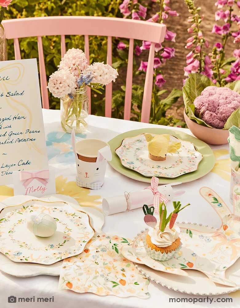 A spring Easter themed party table featuring Momo Party's Elegant Floral Party Collection including dinner plates, side plates, napkins and bunny shaped plates, on the table there are spring flowers, Easter inspired cupcakes, bunny shaped party cups and bunny shaped party crackers, makes this a perfect inspo for an elegant Easter celebration.