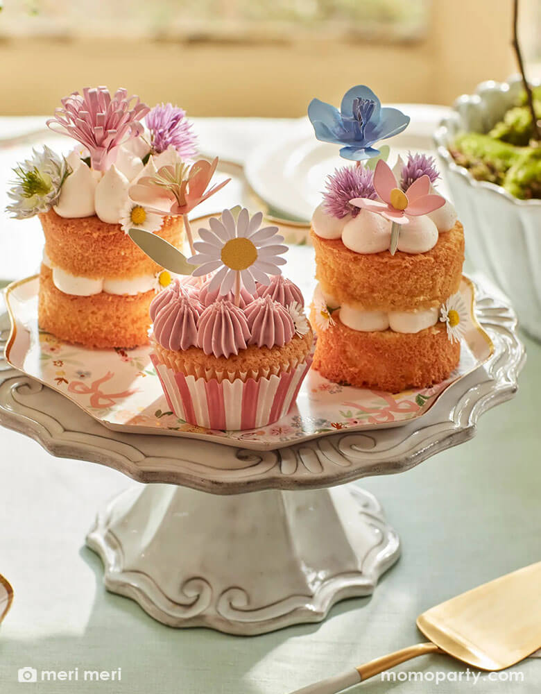An elegant spring inspired party table featuring a vintage ceramic cupcake stand which hold some beautiful cupcakes and desserts topped with Momo Party's flower garden cupcake toppers by Meri Meri. With Momo Party's elegant floral side plate below it, it makes a darling inspiration for a spring gathering or Easter celebration.