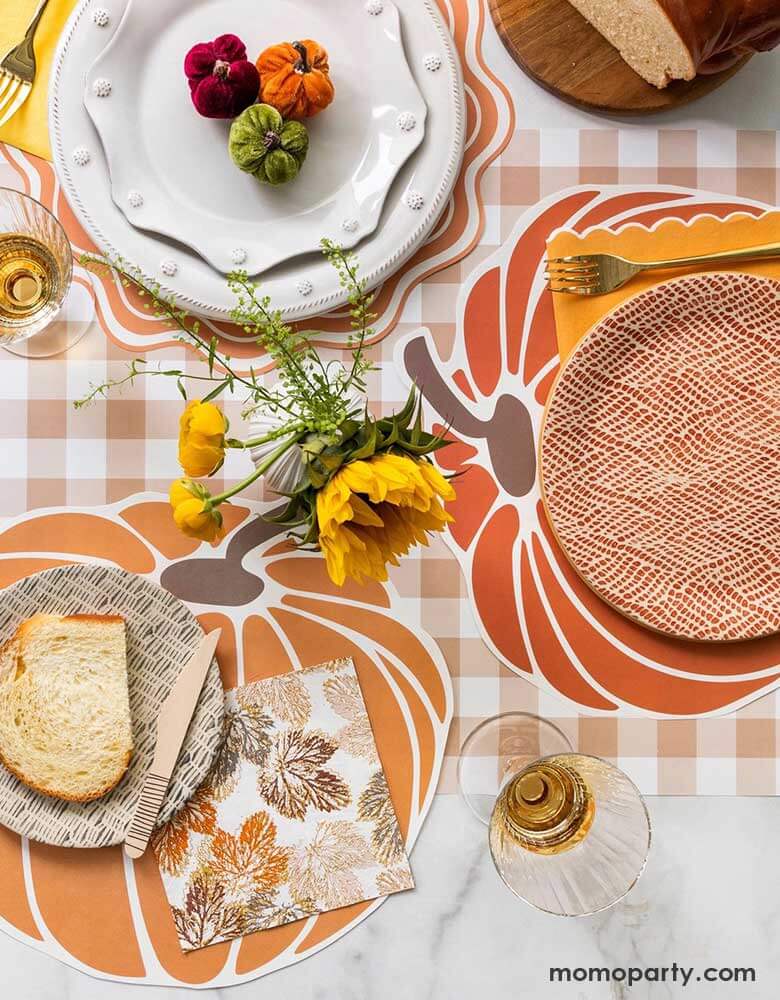 A beautiful fall tablescape featuring Momo Party's fall themed tableware including the pumpkin shaped paper placemats, maple leaf napkins and brown gingham table runner, with fall flower bouquet and pumpkin decorations, this makes a great inspo for a gorgeous fall party or Thanksgiving gathering table decoration idea. 