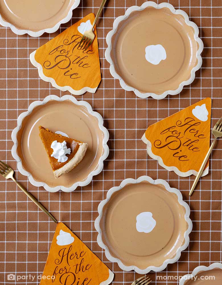 A fall inspired party tablescape featuring Momo Party's pie shaped plates with "Here for the pie" pie shaped napkins on a brown gingham checkered tablecloth. Making this a perfect inspo for a Thanksgiving or Friendsgiving gathering table setting this autumn season.