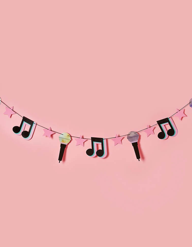 Momo Party's 6.5 ft let's day party banner featuring musical notes, microphone, pink star pennants by Hooty Balloo, with a pink background. This banner is perfect for a teenagers and preteens' dance party, Taylor Swift themed, or TikTok inspired party.