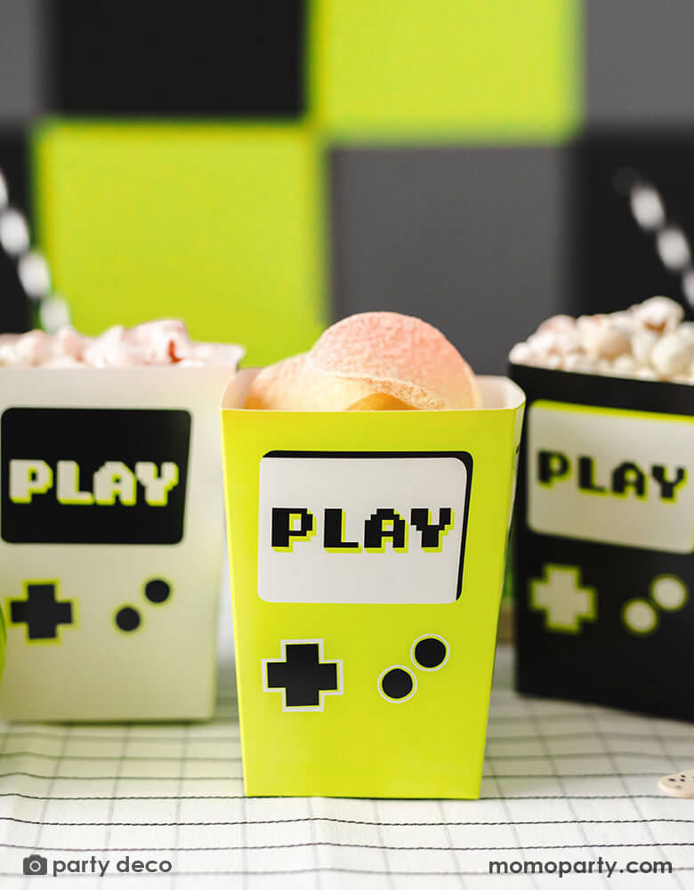 Momo Party's 2.75 x 2.75 x 4.75 inches video game snack boxes by Party Deco. These Game Boy shaped snack boxes in three different colors of black, neon yellow and gray are great for holding party snacks like chips, popcorn, candies and more. They're perfect for kid's video game themed parties.