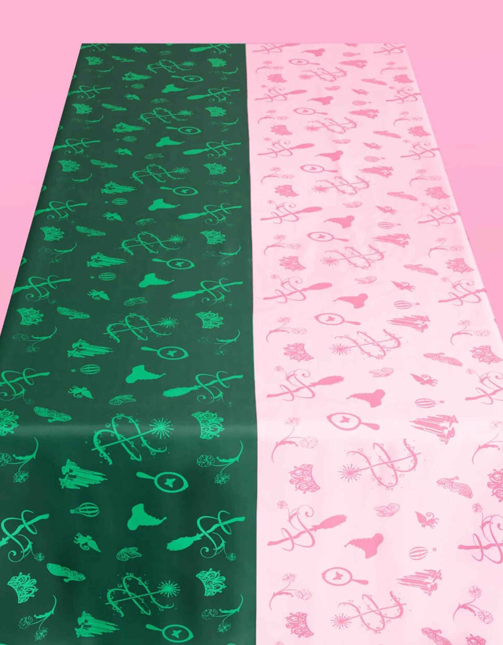 Momo Party's two patterned Wicked party tablecloth, one green with Wicked themed patterns and the other pink, on a pink background.