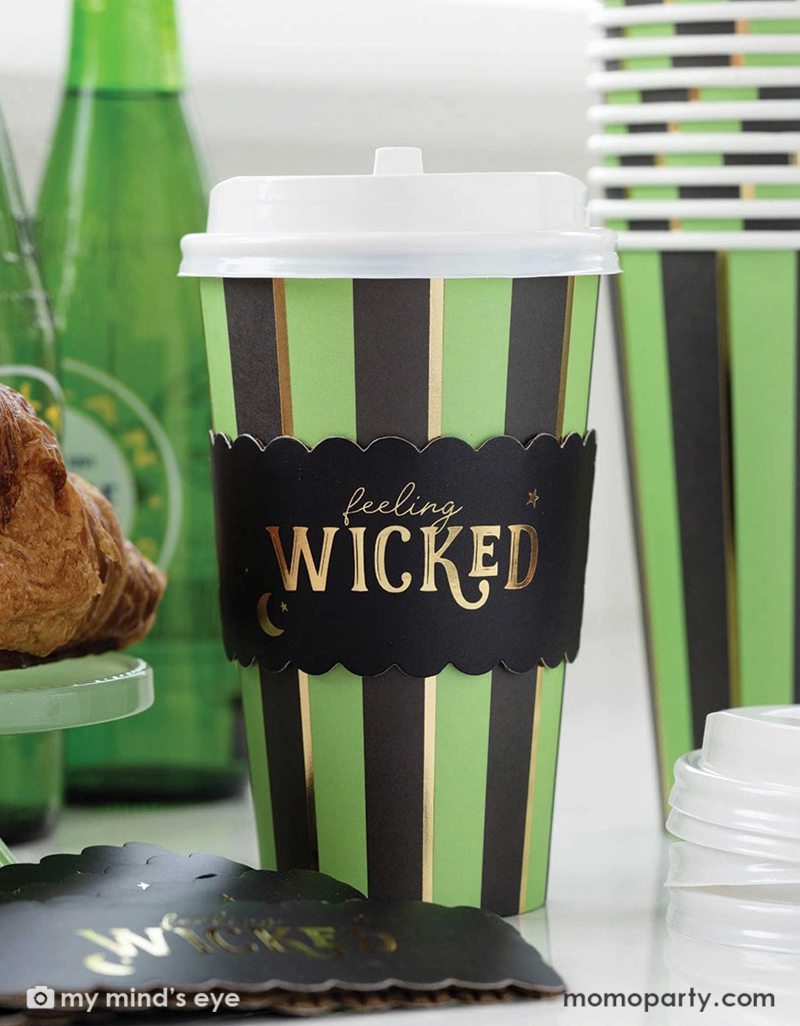 Momo Party's 12 oz Green and black striped Feeling Wicked party to-go cup with 'feeling WICKED' text on the side, surrounded by festive Wicked themed party decors. Perfect for a spooky fun celebration this Halloween.