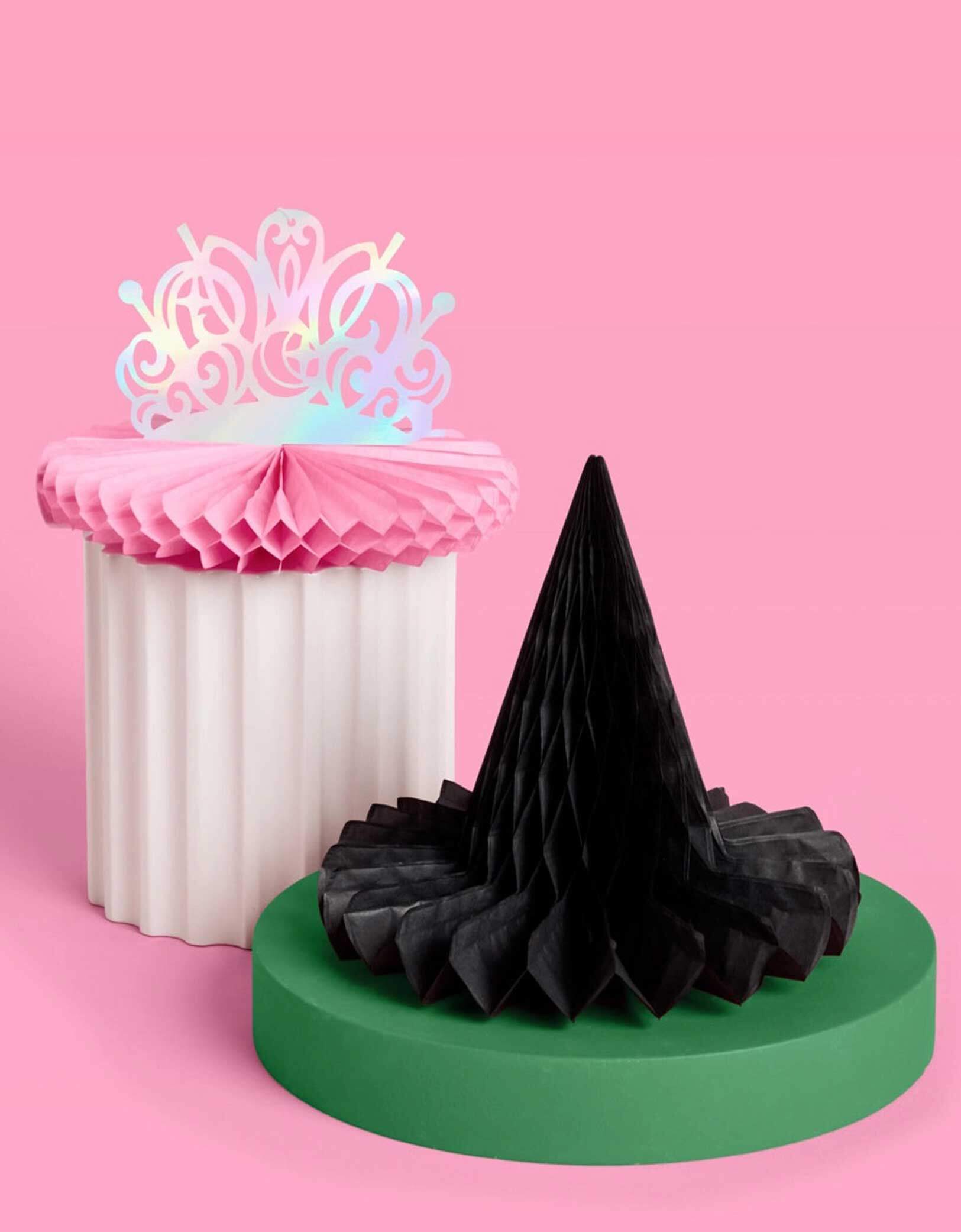 Momo Party's Wicked Pink Tiara & Black Witch Hat Honeycombs on a pink background. Featuring whimsical designs inspired by Glinda’s sparkle and Elphaba’s iconic style, these decorations add a magical touch perfect for fans of the beloved Wicked musical. Easy to unfold and display, they create an enchanting atmosphere that will make your celebration truly spellbinding.