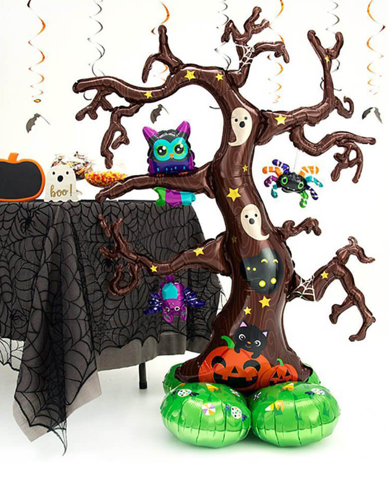 Anagram 62″ Creepy Tree Airloonz balloon Featuring owl, bat, spider and ghost, bat over a Creepy Tree, stands next to a halloween party table with black web table cover, candies, and pumpkin food jar. for a Halloween party, Witch Party, Haunted House Party.