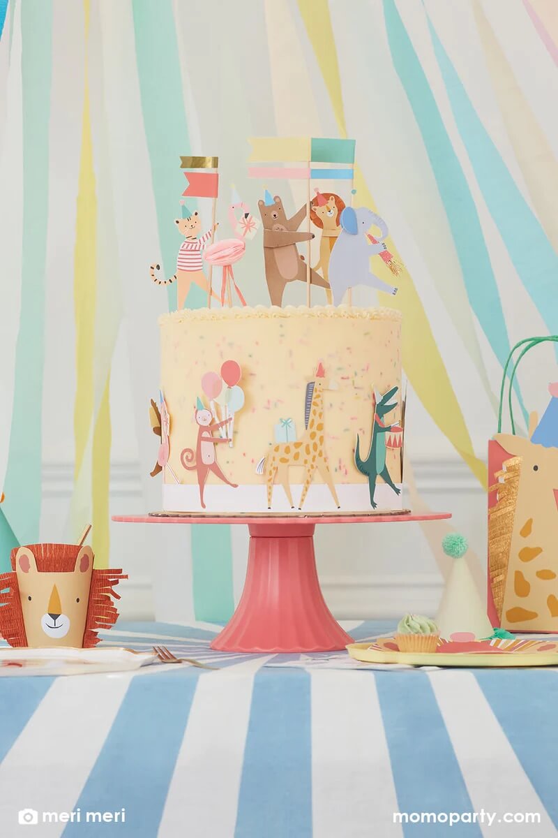 Momo Party Animal Parade themed birthday party table, with a cake decorated with Animal Parade Cake Wrap & Toppers, a lion cup from Animal Parade Character Cups set on the left, and a giraffe party bag from the Animal Parade Party Bags on the right side of the table. These modern and cute design party supplies from Meri Meri of Animal Parade Collection are perfect for kid's zoo, safari, or jungle themed birthday party, or even baby's "Wild One" first birthday party or a "Two Wild" second birthday party!