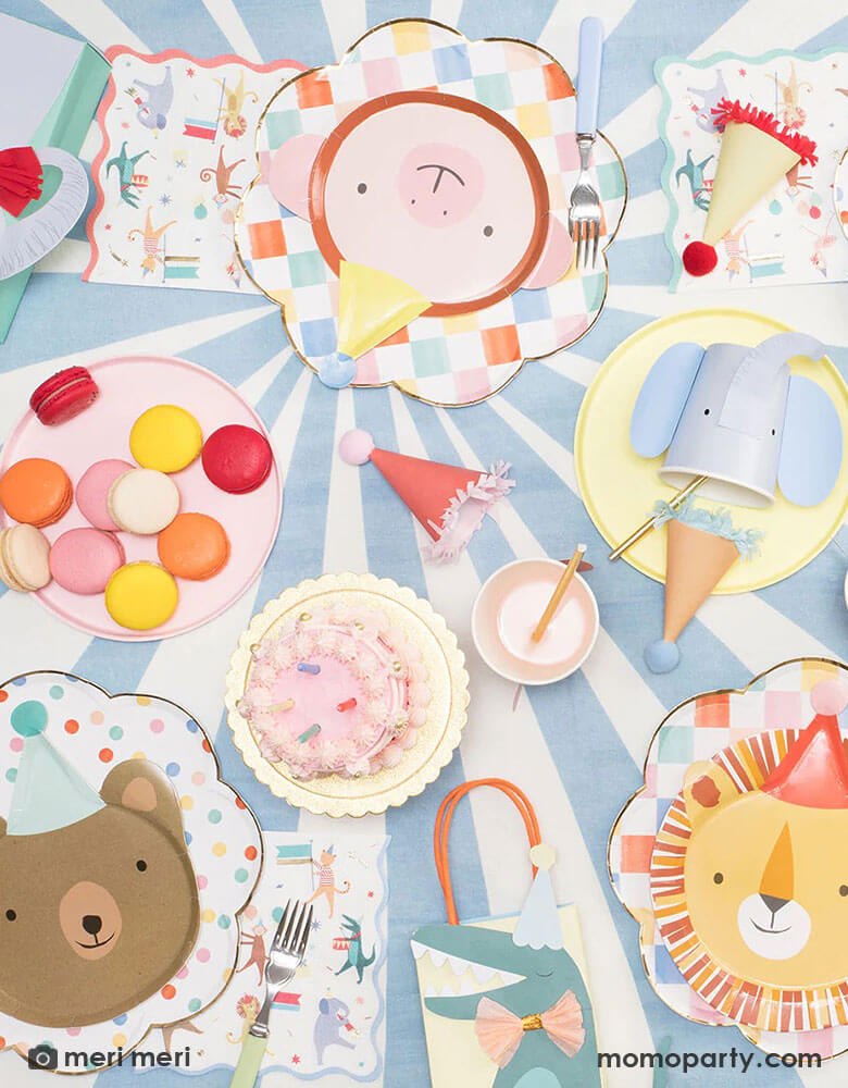A flatlay photograph of a festive party animal themed party table filled with Momo Party's Animal Parade collection including animal die-cut plates, animal shaped party cups, Animal Parade party bags and Animal Parade large napkins by Meri Meri.