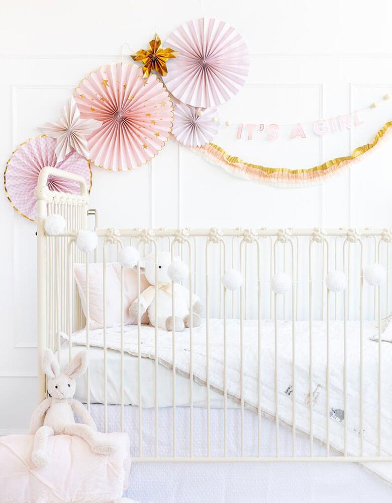 Baby girl's nursery decoration ideas featuring my mind's eye baby pink paper fans and it's a girl banner on the wall