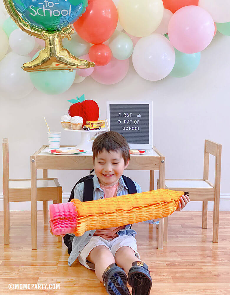 Boy wearing back pack Boy at his 1st day of school celebrationplaying with a Devra Party 24" Back To School Pencil Shaped Honeycomb Decoration