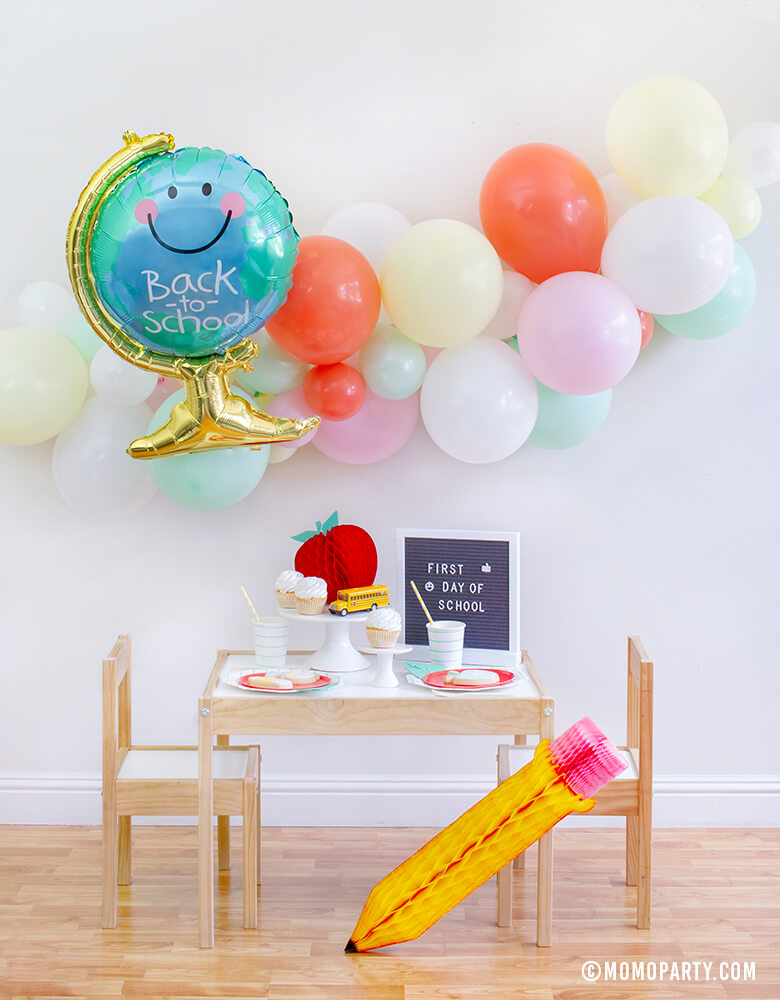 Momo party Back To School  Party Box with Anagram Back To School Globe Foil Mylar Balloon, 6ft long Balloon Garland Assorted in Pastel Yellow, Pink, Mint, Carol, White Latex  Balloon for Backdrop decoration, Letter board with "First Day of School" sign, Oh happy day Cherry Red side plate, Aqua Striped Large Plates and cups, Leaf Napkins as tableware, Honeycomb Apple, cupcakes, and school bus toy on cake stand for a Modern Back to school Party Celebration