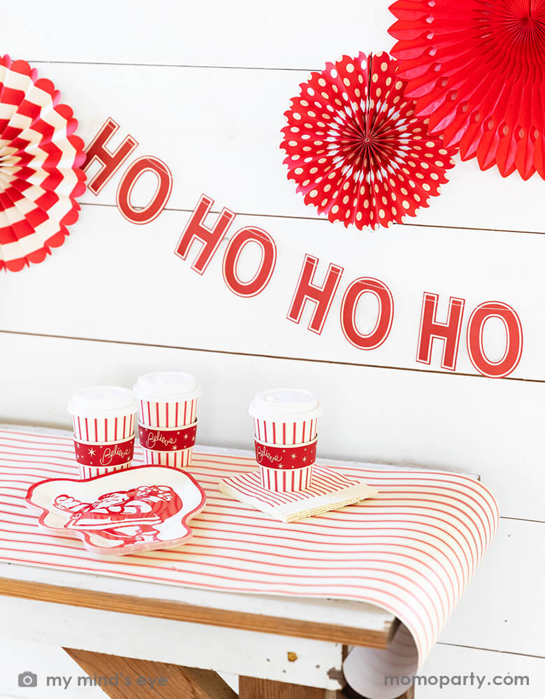 Holiday home decoration with ED STRIPE COZY CUPs and BELIEVE 9" SANTA PLATE over the Believe Christmas Red Striped Table Runner. And Believe Ho Ho Ho Banner and Believe Christmas Paper Fans hanging on the wall. Modern and stress free holiday party supplies from momoparty.com 