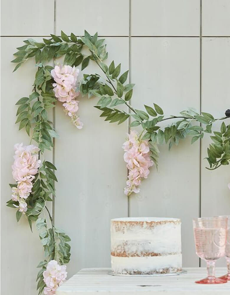 Boho baby shower with Ginger Ray - Blush Pink and Green Wisteria Foliage Garland decorated on the wall, and a naked buttercream cake with drink in the pink glasses on the table. Measuring at 6ft long, this beautiful garland is fully packed with gorgeous wisteria and green foliage, perfect to create a lustful draping foliage look. It's great for a spring gathering, girl's birthday, baby shower or bridal shower!  
