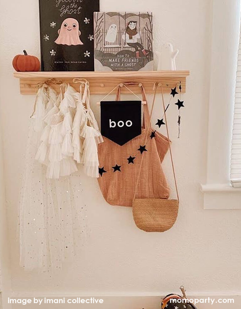 Kid's room wall shelf hanging with girl's beautiful tutu dresses, a black canvas Boo hang Sign,  black  star banner, Woven bags. And  a pumpkinhalloonween books, a cute white ghost figures. These modern unique halloween product are so fun for your little one's room decoration, party decoration, and instagram worthy photos for you halloween celebration memories. Sell from Party Boutique Online at momoparty.com