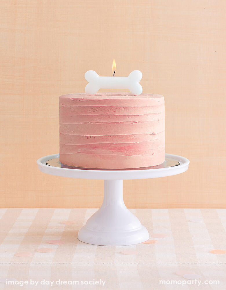 buttercream cake in light coral color with Bow Wow Large Candle from Jollity & Co Party Boutique - Daydream society- Bow Wow collection on top. This dog bone shaped white large candle 