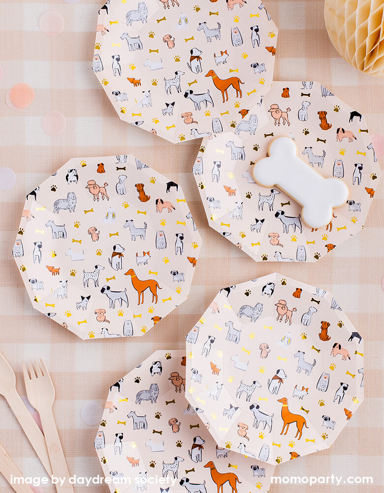 Top view of Bow Wow Dog Small Plates from Jollity & Co Party Boutique - Daydream society- Bow Wow collection. Printed with variety breed of dogs and dog paws in modern illustrations with a warm neutral color palette and gold foil elements, there is a dog bone shaped cookie on the plate, wooden utensils, ivory colored honeycomb decoration, confettis on top of Natural Cabin Check Tablecloth. These puppy dog party ware are definitely best for a pet lover party, dog lover party, pets party!