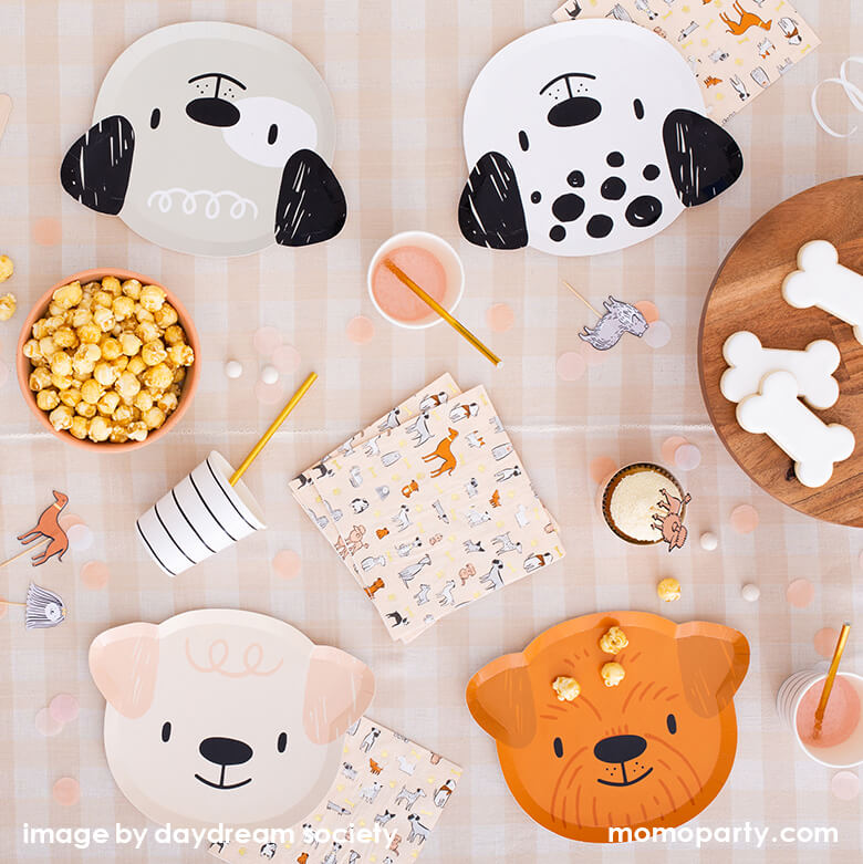 Bow Wow Dogs themed party table filled with Bow Wow Dog shaped Paper plates in 4 different dog design, cute dog toppers, popcorns in a bowl, black striped paper cups with gold foil straw. dog bone shaped cookies on the wooden cake stand, wooden utensils, confettis on top of Natural Cabin Check Tablecloth. These modern Dog Birthday Party Supplies are perfect for a dog lover, a dog themed birthday party, Let's Pawty birthday party, adorable puppy themed party