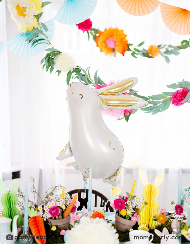 A beautiful Easter table decorated with spring flowers and honeycomb Easter egg, bunny and carrot decorations by Party Deco, with Momo Party's adorable 33 x 32" bunny shaped foil balloon by Party Deco in front of floral garland sets and tissue paper bunting garland, it makes a perfect inspiration for Easter celebration ideas.