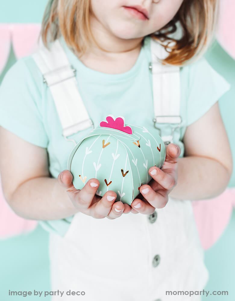 A girl holding a Party Deco Cactus Favor Boxes. This pastel mint Cactus-shaped party supplies are sure to spice up your fiesta party décor. and gift them to guests as they leave the fiesta.