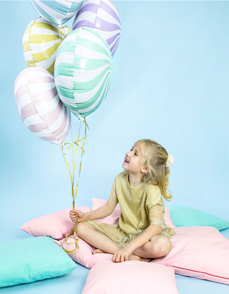 Girl holding assorted candy foil balloons by Party Deco