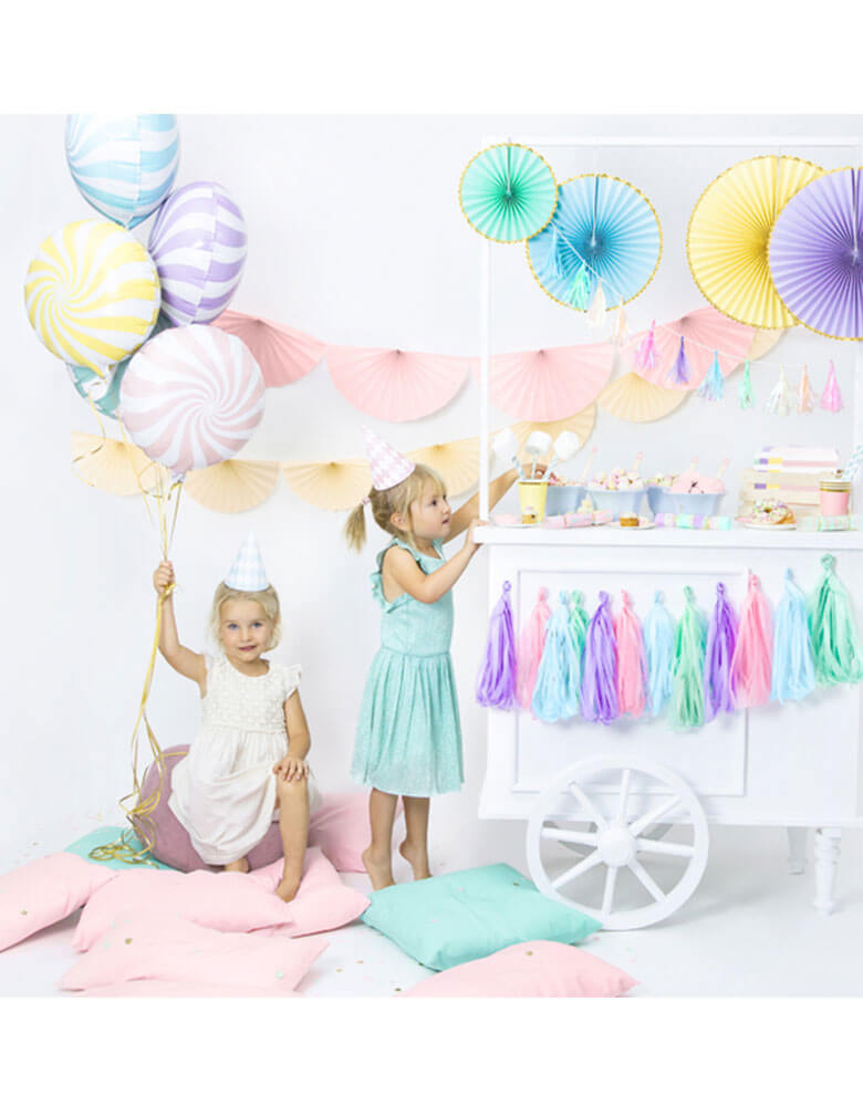 A sweets themed party with candy foil balloons and dessert cart filled with pastel decorations
