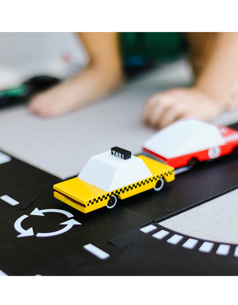 Kid's playing Candylab Candycar Yellow Taxi and red racer on a toy asphalt road