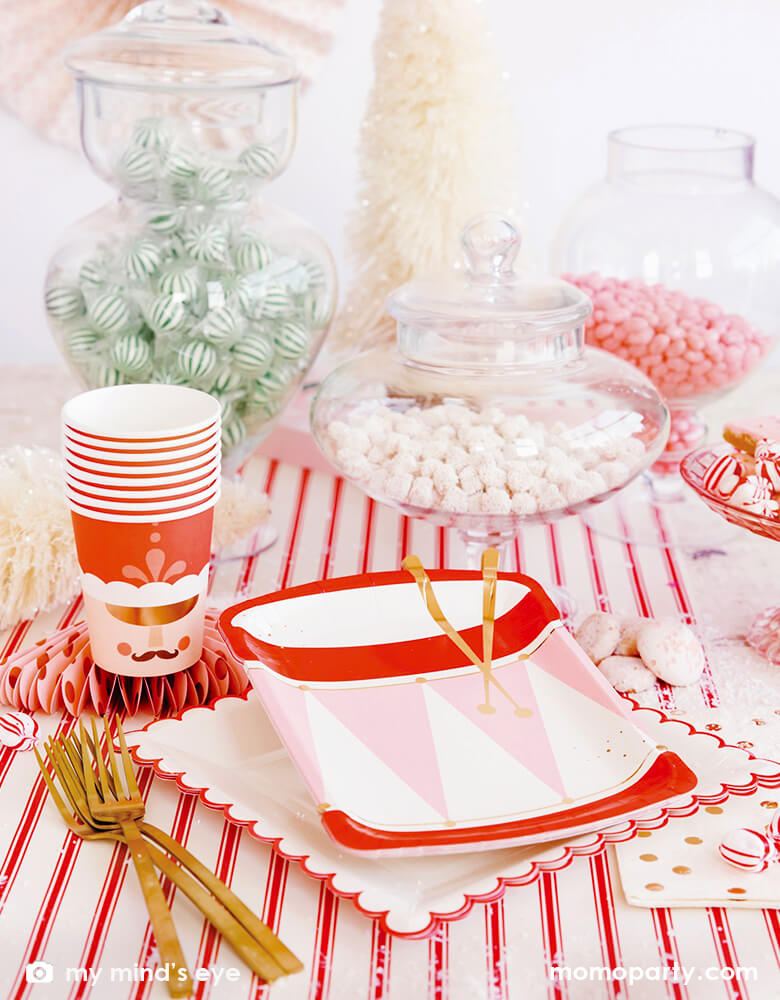 Holiday Christmas Table close up of My Mind's Eye Nutcracker Drum Shaped Plates layered with Believe White & Red Scalloped Large Plates, with Nutcracker Napkins and Nutcracker Soldier Cups, sweets in the clear jars, Christmas brush trees in white, and golden folks over the Believe Christmas Red Striped Table Runner. These Morden and high quality party supplies with cute design in pink and red tone are perfect for holiday family celebration with kids. Shop Holiday partyware, party supplies at momoparty.com
