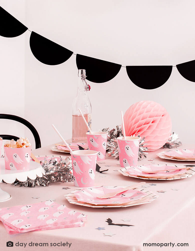 A spooky yet adorable Kid's halloween party table decorated with black scalloped shaped bunting garland and a table filled with Daydream Society's Spooked collection featuring ghosts design on a bright neon pink background. Perfect inspiration for a pink Halloween celebration