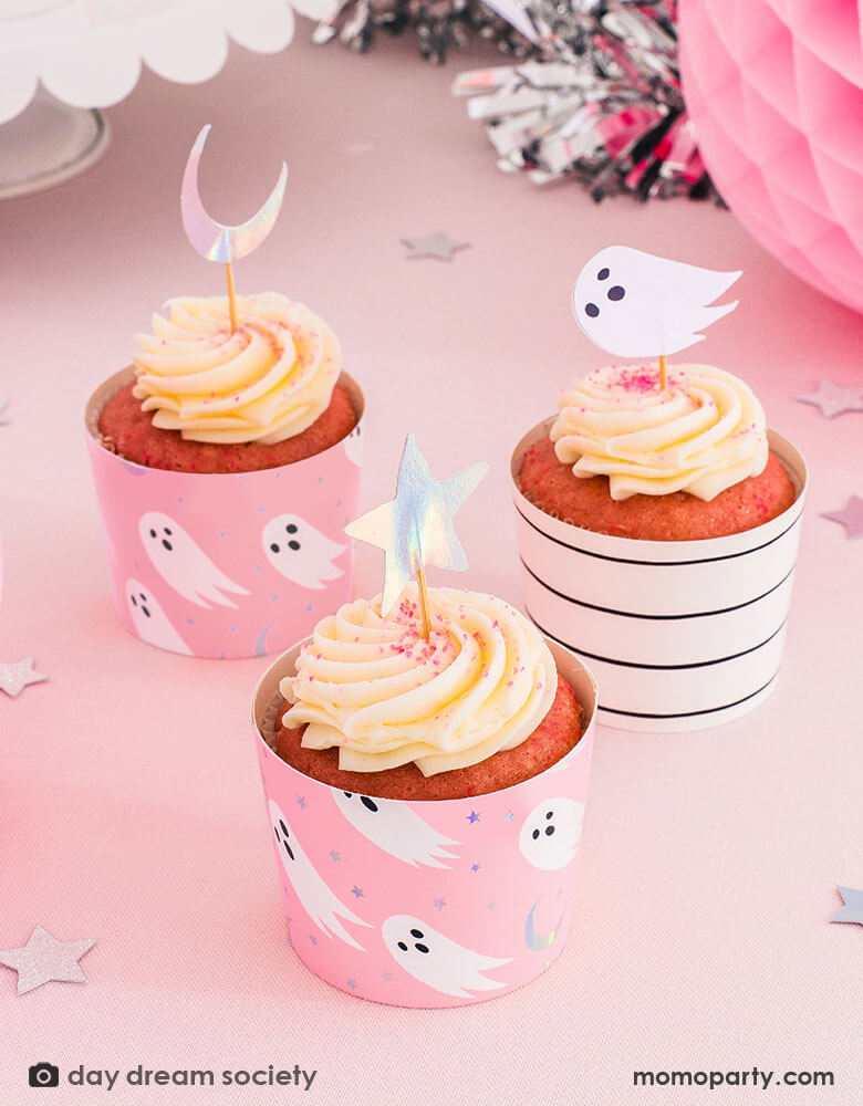 A pink Halloween party table with Daydream Society Pink Halloween Spooked Cupcake Decorating Set  featuring ghost design and iridescent moon and star with a neon pink background 