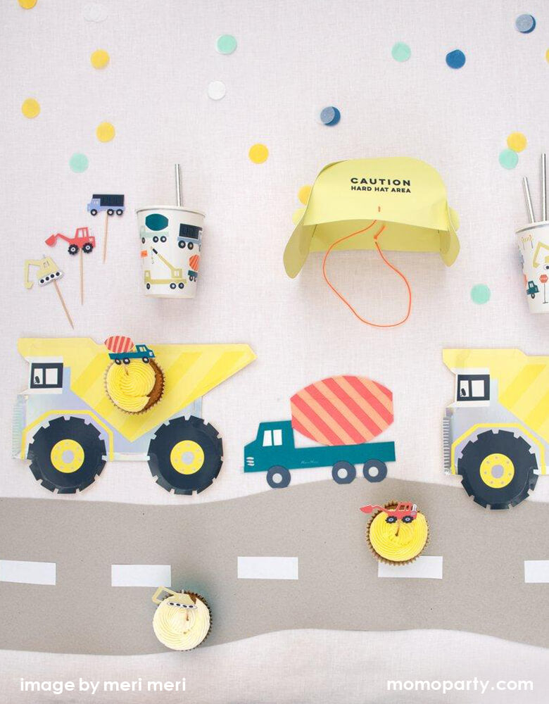 Kid Dig In Construction party table set up. There are cupcake with Construction Cupcake topper on the Meri Meri Dumper Truck Plates, Construction Party cups and Construction truck napkins, and a yellow Construction Party Hat, confetti. what a Fun modern partware for a kid's construction themed birthday party, Dig in birthday party, big construction vehicle lover, boy's birthday party