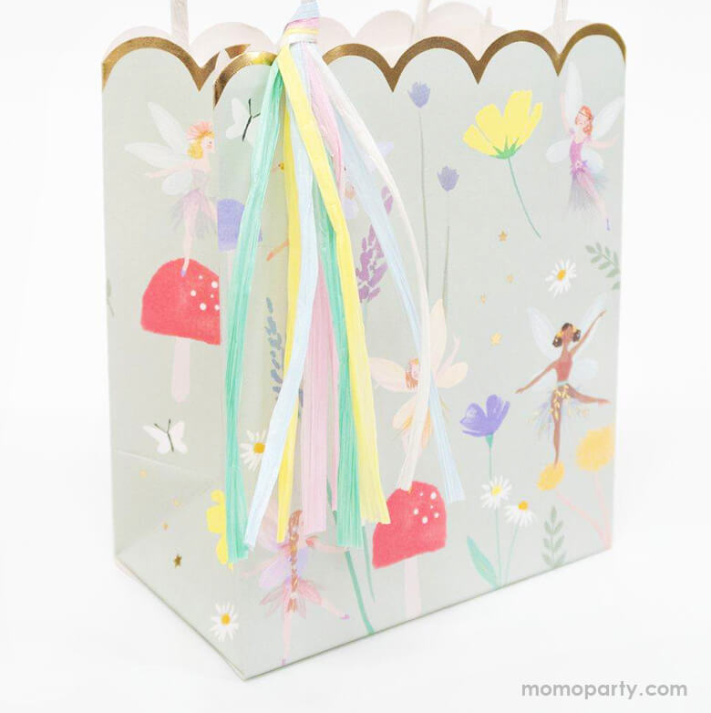 close up details of Meri Meri Fairy Party Bags. They are crafted with a stylish scallop edge and feature illustrations of dancing fairies, flowers and toadstools, and golden foil detail. The bags have twisted paper handles and gorgeous raffia tassels.