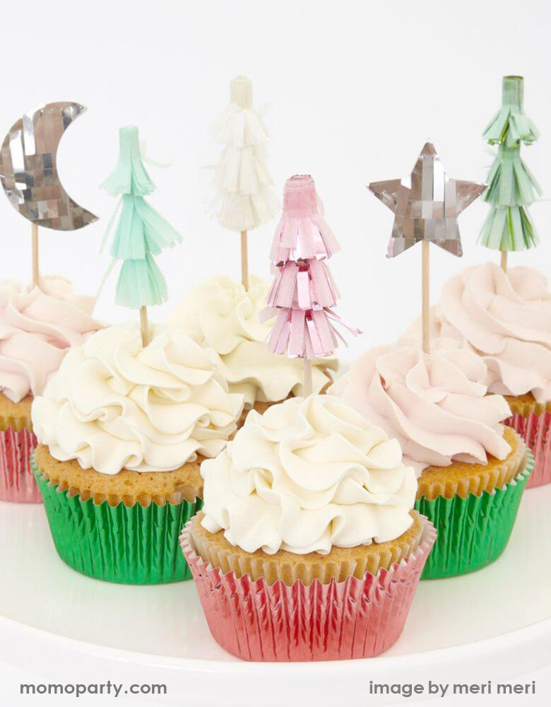Close up of A Set of cupcakes topped with Meri Meri Festive-Tree-Cupcake-Kit featuring Christmas tree, moon and star toppers in pink silver and mint foil