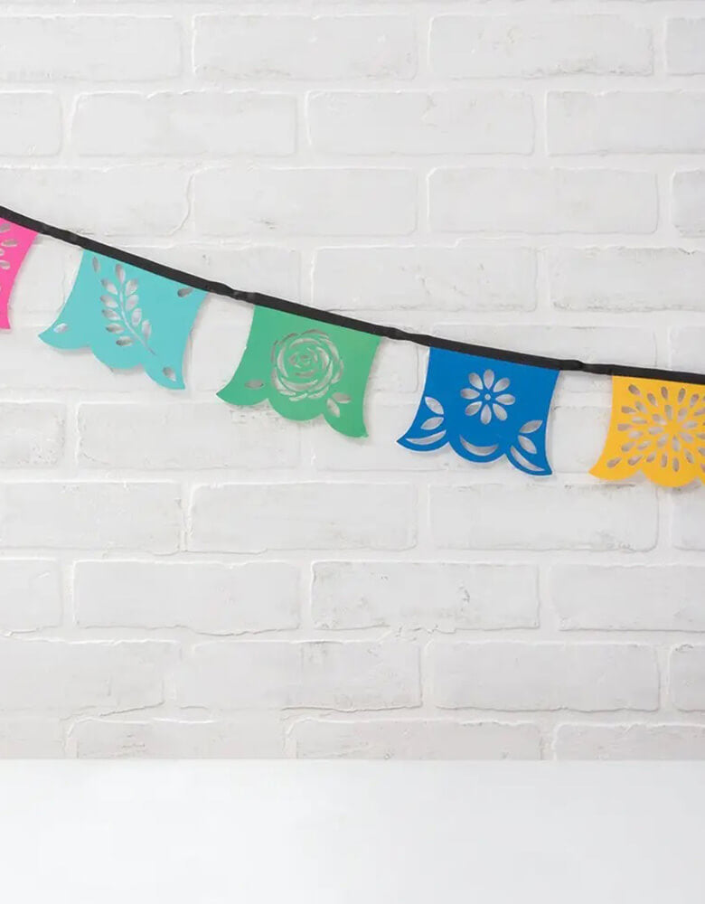 Momo Party's 79" Fiesta Colorful Party pennant banner by Weddingstar Inc. Made in the papel picado style, the colorful fiesta themed banner has four unique flower designs cut out of the vibrant teal blue, pink, red, yellow, dark blue, and green paper cardstock pennants in a dynamic style. Hang this banner inside your house, outside in the garden, across doorways, along table edges, or artfully placed on walls.