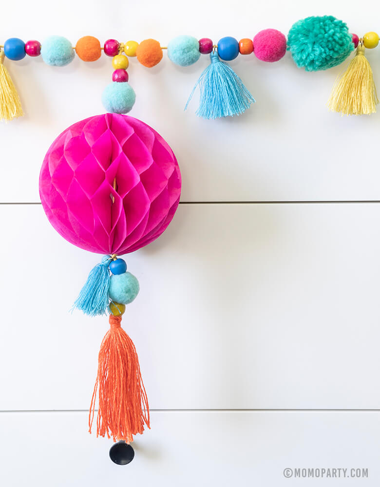 close up look of Talking Table_Boho Fiesta Pom Pom Garland with Pom poms and tassels combined with bead and paper honeycomb details for Fiesta party or cinco de Mayo celebrations or home decoration 