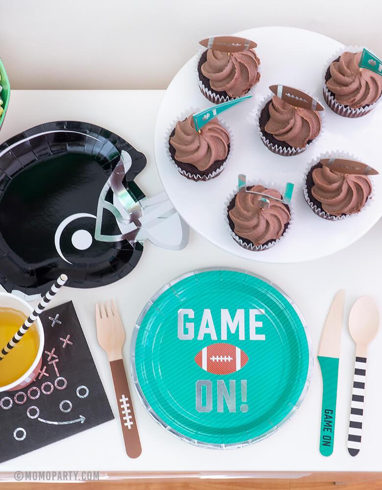 Football Party set up idea with Green Game on Football Party Paper Plates, Black Game Play Napkins, Football Tailgate Helmet Appetizer Plates, chocolate Cupcake with Tailgate Treat Picks, Football Tailgate Wooden Cutlery Set, simple modern party ware for kid football themed birthday party or super bowl celebration