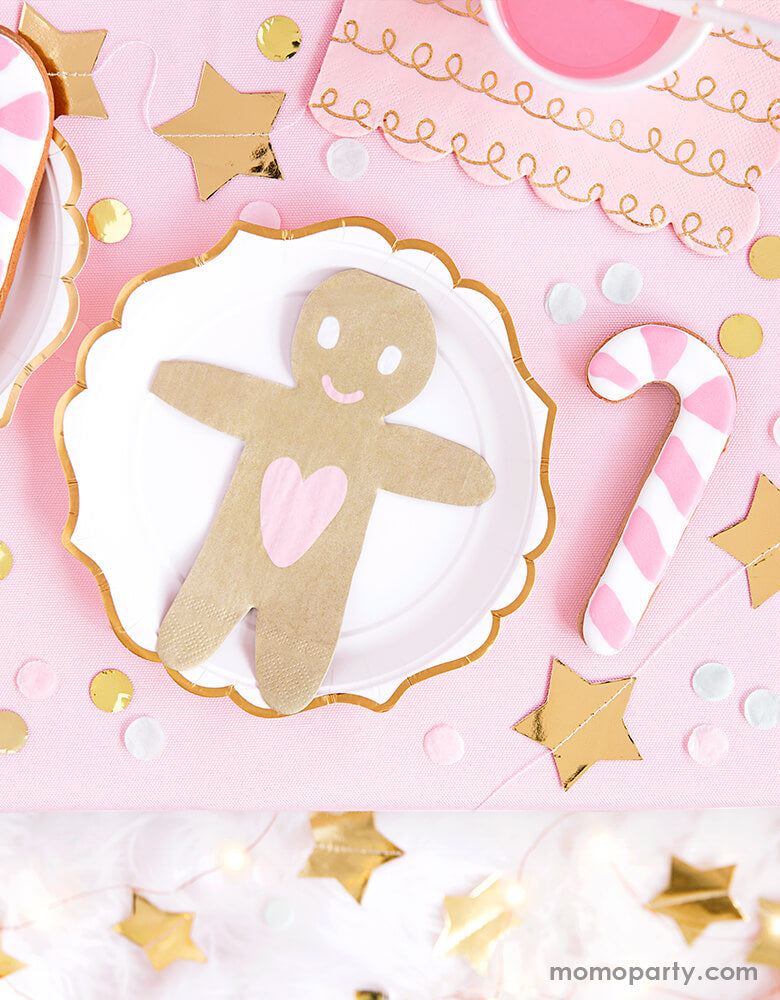 A pink Christmas party table set up featuring Party Deco's Gingerbread-Man-Napkin with star banners and candy cane sugar cookies around