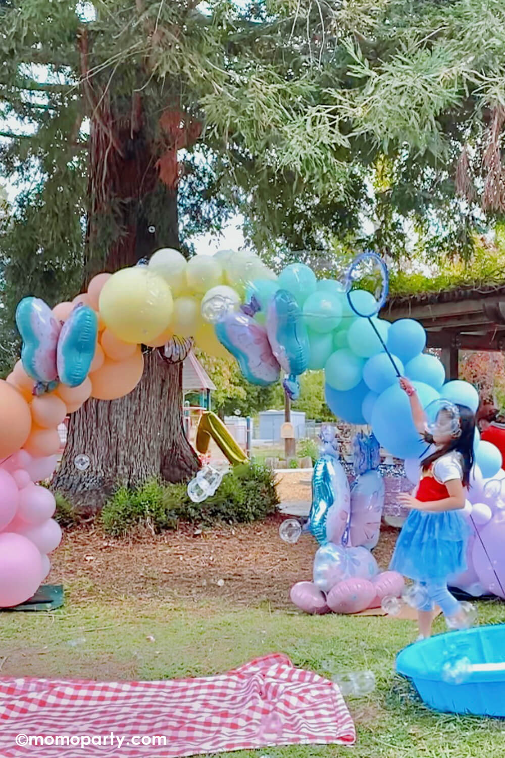 A girl's 7th butterfly themed birthday party balloon set up featuring a jumbo pastel rainbow balloon arch with Anagram's butterfly Airloonz foil balloon, altogether creates a whimsical magical garden scene for a gorgeous event.