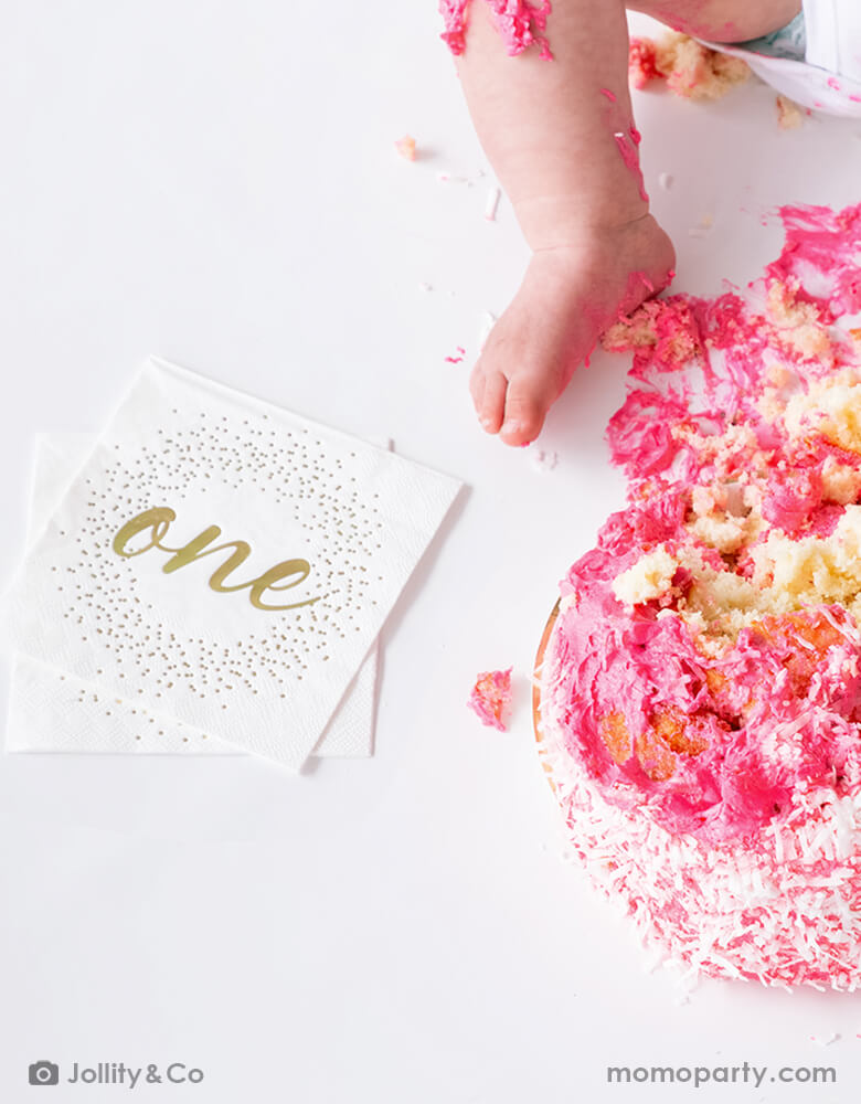 First birthday pink smash cake with Jollity 7-inch onederland gold round dessert plate with gold script "one" on it and gold foil confetti illustration around it, it's gender neutral and perfect for baby's first birthday party celebration!