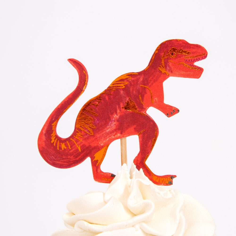 Close up details a cupcake decorated with a Red T-rex cupcake topper from Meri Meri Dinosaur Kingdom Cupcake Kit.