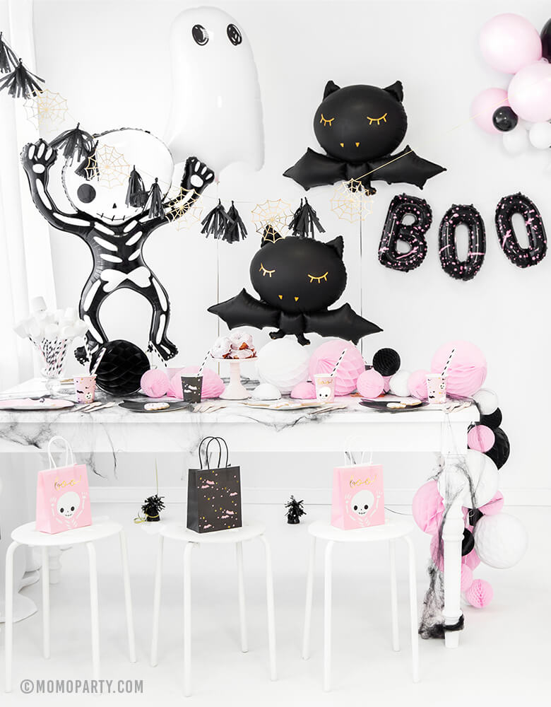 a Pink Halloween party decorated with Party Deco Halloween Skeleton shaped Foil Mylar Balloon, Halloween Ghost Foil Mylar Balloon, Black bat foil balloon, and golden spiderwebs and black tassels garland. BOO Letter Foil Balloon Set. there are pink ghost and black bats gift bags on each chair.  These cute halloween balloons also perfect for Kid-Friendly modern spooky halloween party, trick-or-treating halloween party, nightmare before christmas party, witch themed party and all halloween related celebrations