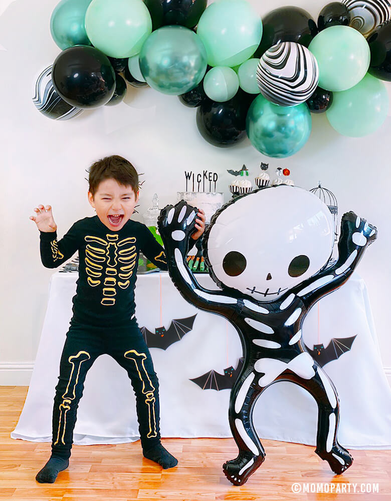 boy dance with Party Deco - Halloween Skeleton Foil Mylar Balloon, The balloon is designed in the shape of a funny skeleton and measures 33 x 39 inches. Add this modern fun skeleton foil balloon to your or your kid-friendly modern spooky halloween party, trick-or-treating halloween party, nightmare before christmas party, witch themed party and all halloween related celebrations