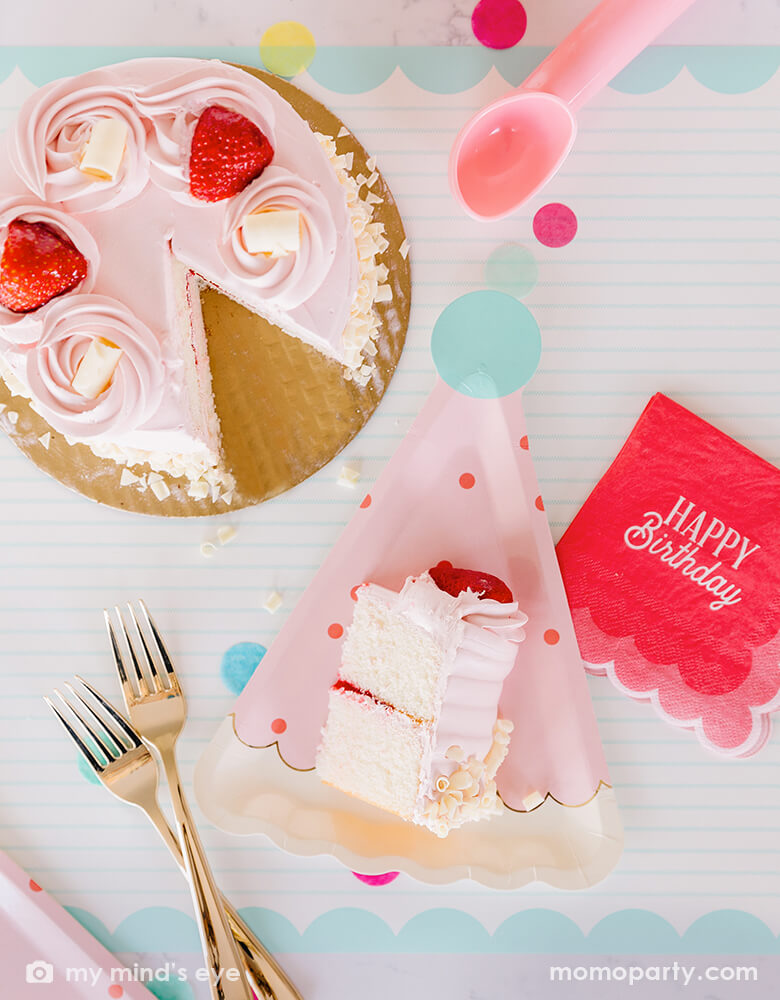 A darling birthday party table with a pink strawberry buttercream birthday cake, filled with cheerful confetti in mint, coral and yellow and My Mind's Eye coral scalloped Happy Birthday napkins with pink birthday hat shaped party plates - a perfect size for serving birthday cakes - all makes a great modern and simple inspiration for a girl's birthday celebration.