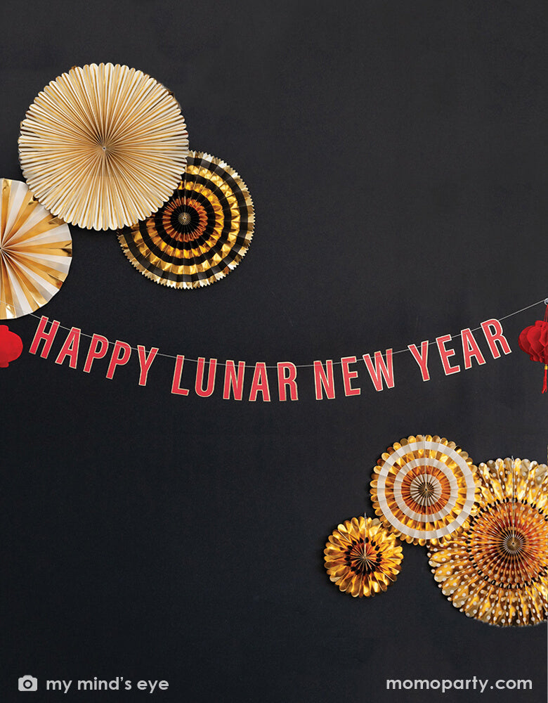 Momo Party's Happy Lunar New Year Banner by My Mind's Eye and TUXEDO BLACK AND GOLD PARTY FANS over a black wall. With a "Happy Lunar New Year" word banner and two red honeycomb lanterns, it sets a perfect scene for your Lunar New Year celebration!