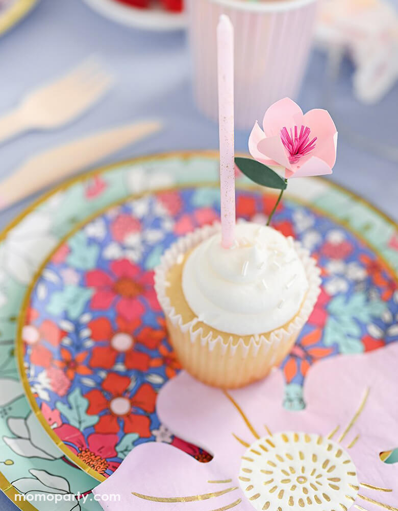 Floral Garden themed party close up look of a cupcake decorated with Coterie In Full Bloom Mini Topper and pink glitter candle on top of In Full Bloom plates and In Full Bloom flower shaped pink Napkin. This garden-inspired modern design are perfect for spring party, garden themed party, fairy themed party, mother's day, bridal shower, baby shower or any morden parties.