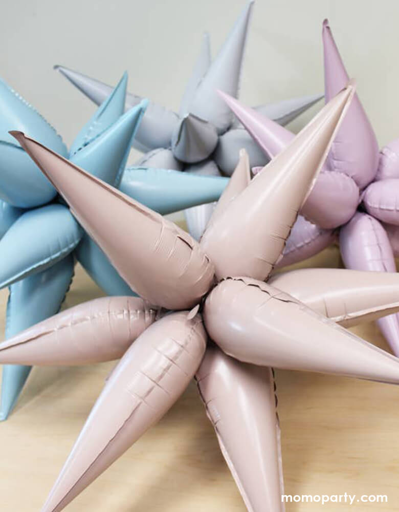 Set of 4 Momo Party's Jumbo 12 Point Starburst Foil Balloons in Blush, White, Pastel Pink and Pastel Blue colors display on the table. These 26 inches jumbo starburst foil balloons by Ellie's Party are simply a show-stopper for any celebration